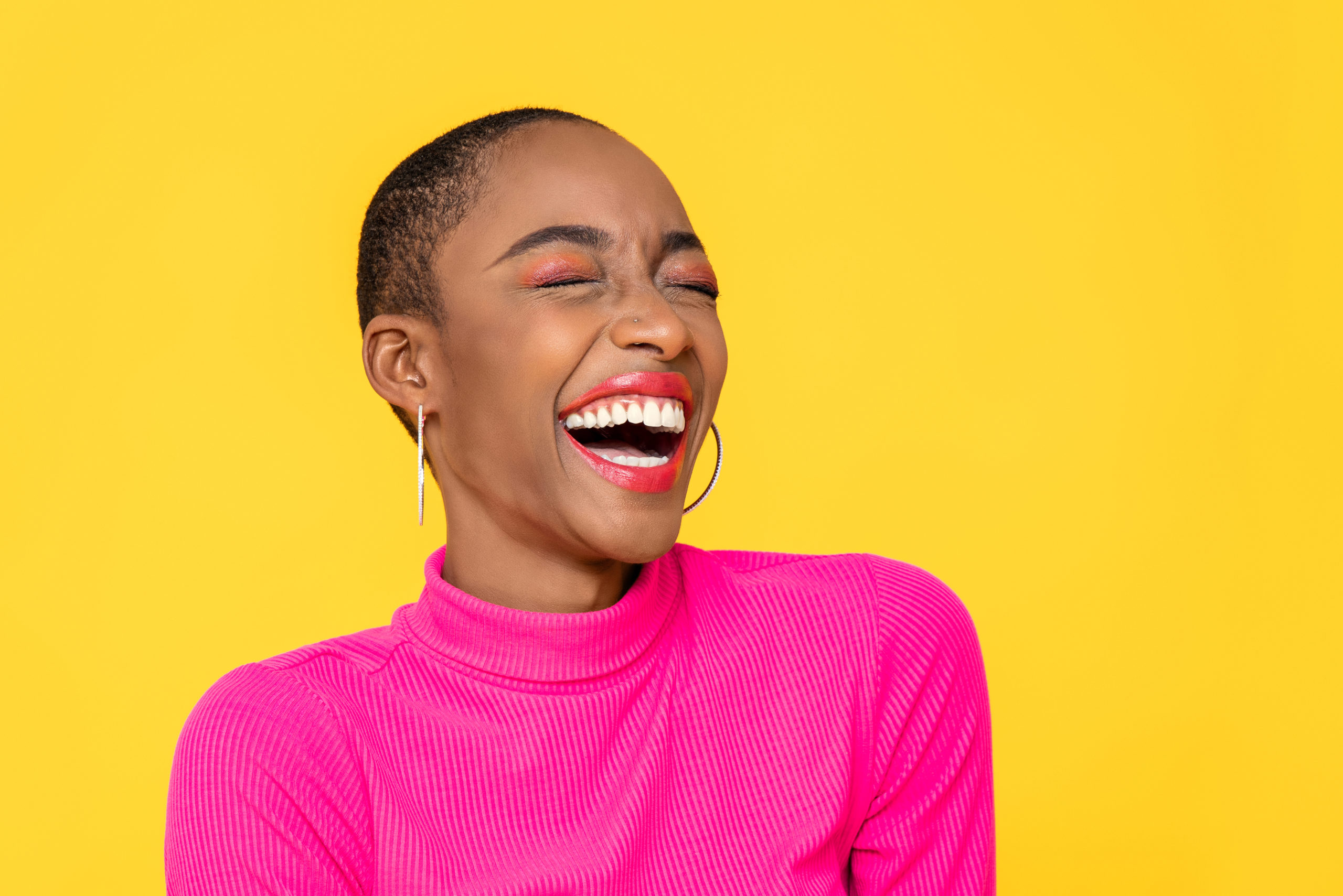 Women in a pink shirt laughing in front of a yellow background