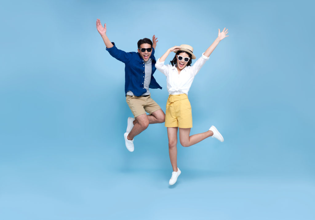 Man and woman jumping for joy in front of a blue background
